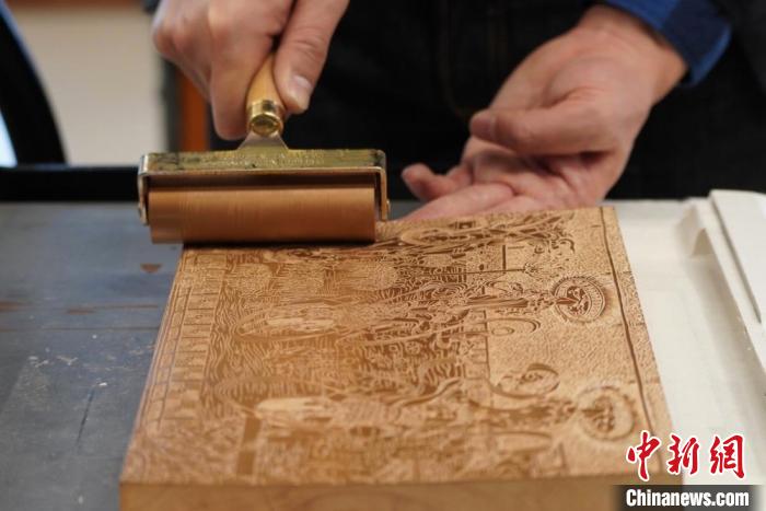 圖為徐晉林工作室工作人員正在給雕好壁畫的版面滾油墨?！【琶赖┰?　攝