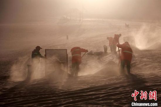 圖為敦煌市鳴沙山月牙泉景區(qū)“駱駝保姆”清理駱駝糞便?！垥粤?攝