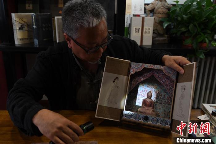 圖為讀者出版集團(tuán)讀者晉林工作室獨(dú)立出品人徐晉林，展示互動(dòng)性強(qiáng)的敦煌題材手工書。(資料圖) 楊艷敏 攝