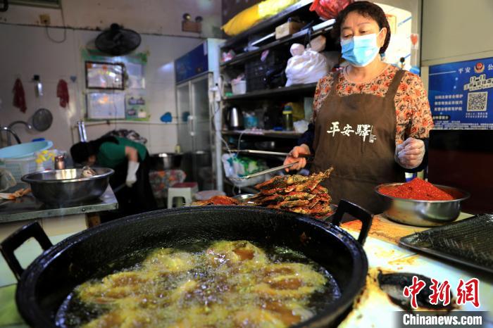 圖為平安驛·河湟民俗文化體驗(yàn)地內(nèi)的商戶炸干板魚?！⊙Φ?攝